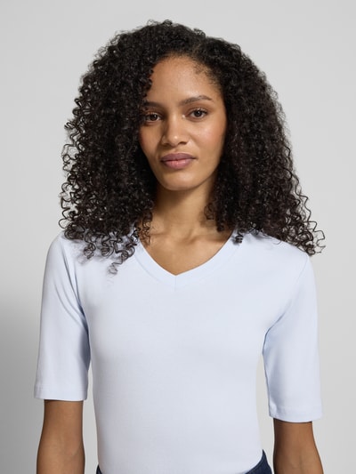 Modelka nosi T-shirt mit V-Ausschnitt von Christian Berg Woman, mieszanka bawełny i elastanu, krój regular fit, dekolt w serek, rękaw o dł. 1/2, długość tyłu w rozmiarze S: 55 cm, jasnoniebieski kolor, gładka tekstura. Nahaufnahme górnej części ciała.