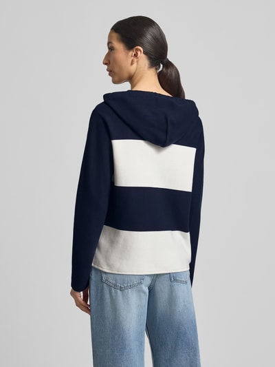 Frauenmodel trägt Strickpullover mit Kapuze und Streifenmuster von monari, Reine Baumwolle, Regular-Fit, Logo, Rückenlänge 60 cm, Ärmellänge 59 cm, Ganzkörperansicht Rückansicht.
