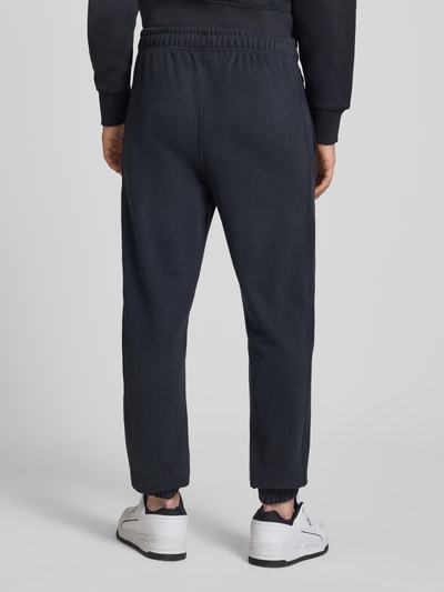 Männermodel trägt Sweatpants mit Logo-Stitching Modell 'ORVINIO' von Ellesse in Dunkelblau, Slim Fit, Rückansicht, Baumwoll-Mix.