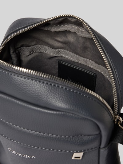 Produktfoto, Herren Handtasche mit Label-Detail Modell 'RAISED REPORTER' von CK Calvin Klein, Hauptfach mit Reißverschluss, feine Narbung, Umhänge-Schulterriemen, Innenfutter aus Stoff, Maße 17x20x7 cm, grau-blau mit silberfarbenen Details