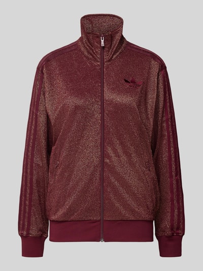 Produktfoto, bluza rozpinana z mieszanki bawełny z metalem adidas Originals, luźny krój, stójka, zamek błyskawiczny, wyhaftowane logo, prążkowane wykończenia, kieszenie zapinane na zamek błyskawiczny, bordowy kolor, lekki połysk, jednolita forma.