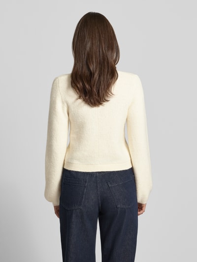 Frauenmodel trägt Strickjacke mit Rundhalsausschnitt Modell 'Ally' von Gina Tricot, cremefarben, Feinstrick, Regular Fit, Rückenansicht Ganzkörperansicht.