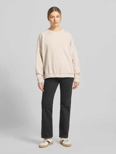 Modelka kobieca nosi Oversized Fit Sweatshirt mit Zier-Bordüren od Smith and Soul, bawełniana mieszanka, kremowy, okrągły dekolt, ozdobne lamówki, pełen widok z przodu.