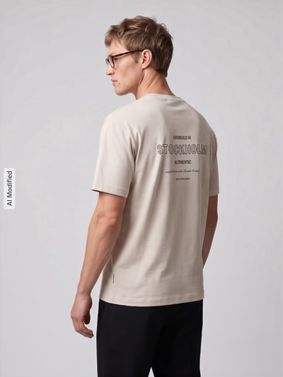 Männermodel trägt Boxy Fit Shirt aus Baumwoll-Mix von Marc O'Polo DENIM in Beige mit Aufdruck, Ganzkörperansicht Rückansicht, KI-modifiziertes Bild.