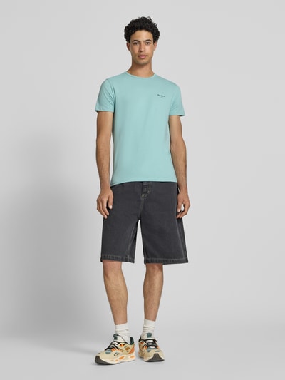 Męskimodel nosi Slim Fit T-Shirt aus Baumwoll-Mix Modell 'ORIGINAL BASIC 3N' von Pepe Jeans, jednokolorowy, nadruk z logo, okrągły dekolt, krótki rękaw, dżersej, mieszanka bawełny, Ganzkörperansicht von vorne.