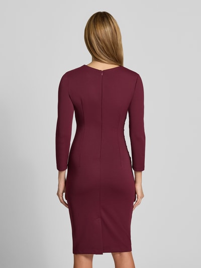 Frauenmodel trägt Cocktailkleid mit Raffungen von Rinascimento in Bordeaux, taillierte Passform, glatte Textur, Ganzkörperansicht Rückansicht. Material-Mix mit Stretch-Anteil, knielang, Rundhalsausschnitt, langärmelig, Rückenlänge 96 cm bei Größe S.