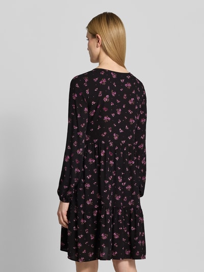 Frauenmodel trägt Minikleid aus Viskose mit V-Ausschnitt von Zero in Schwarz mit pinkem Blumenmuster, taillierter Schnitt, elastische Ärmelabschlüsse, Rückenlänge 80 cm, Brustweite 39 cm, Ärmellänge 60 cm, Ganzkörperansicht Rückansicht.
