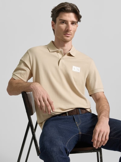 Männermodel trägt Regular Fit Poloshirt mit Knopfleiste von ARMANI EXCHANGE aus Baumwoll-Elasthan-Mix mit Label-Print, Nahaufnahme Oberkörper.