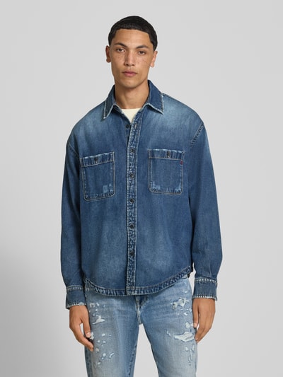 Männermodel trägt Regular Fit Jeanshemd mit Viskose-Anteil von Replay, mittelblaue Waschung, Brusttaschen, Kent-Kragen, Ganzkörperansicht von vorne.
