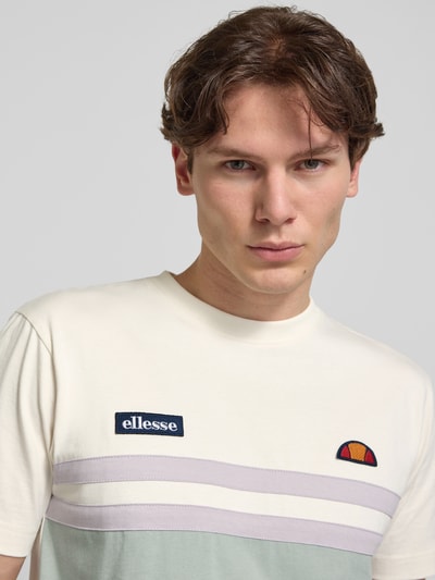 Männermodel trägt T-Shirt mit Label-Stitchings und Rundhalsausschnitt von ellesse, Reine Baumwolle, Regular-Fit, Nahaufnahme Oberkörper. Rückenlänge bei Größe M: 69 cm.