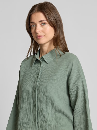 Frauenmodel trägt Loose Fit Hemdbluse aus reiner Baumwolle Modell 'NATALI' von Vero Moda in Optik: Unifarben, Seersucker-Struktur, Knopfleiste, Hemdkragen, 3/4-Arm, Nahaufnahme Oberkörper.