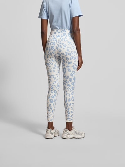 Frauenmodel trägt Leggins mit Allover-Animal-Print von Juvia in Weiß und Hellblau, Slim-Fit, breiter Bund, Knöchellänge, Ganzkörperansicht Rückansicht.