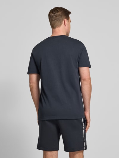 Männermodel trägt Regular Fit T-Shirt mit Logo-Stitching Modell 'Icon' von Under Armour im Baumwoll-Mix, Rückenlänge 72 cm, Ganzkörperansicht Rückansicht.