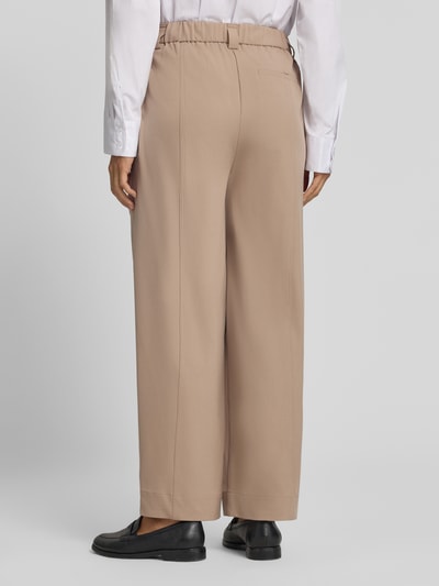 Frauenmodel trägt relaxed Fit Gerade Hose mit Bundfalten Modell 'Metta' von OPUS PANTS in Beige, glatte Oberfläche, Ganzkörperansicht Rückansicht.