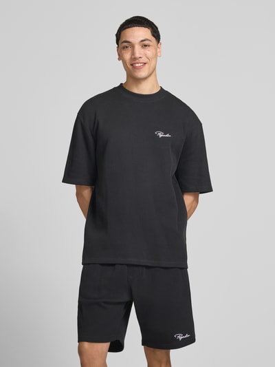 Męskimodel nosi Oversized T-Shirt mit Strukturmuster von Pegador z mieszanki bawełny, krój oversized fit, fakturowany wzór, okrągły dekolt, wyhaftowane logo, długość tyłu w rozmiarze m: 71 cm, widok całej sylwetki z przodu.