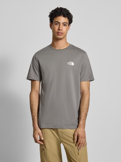 Männermodel trägt T-Shirt mit Label-Print von The North Face aus Baumwoll-Mix, Regular-Fit, gerippter Rundhalsausschnitt, Ganzkörperansicht von vorne.