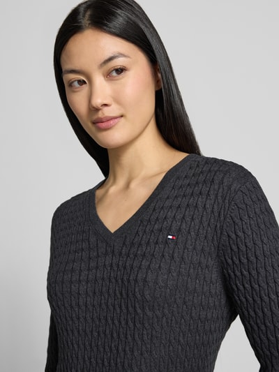 Vrouwenmodel draagt Regular Fit pullover uit puur katoen van Tommy Hilfiger in donkergrijs met kabelstructuur, close-up bovenlichaam. Dames pullover van Tommy Hilfiger