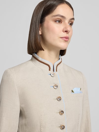 Modelka nosi Slim Fit Blazer aus Leinen-Baumwoll-Mix von WHITE LABEL, mieszanka lnu i bawełny, krój slim fit, stójka, listwa guzikowa, nakładane kieszenie, długość tyłu w rozmiarze 36: 58 cm, szerokość w rozmiarze 36: 46 cm, długość rękawów w rozmiarze 36: 63 cm, jasny beż z niebieskimi i brązowymi akcentami, tekstura lekko ziarnista. Zbliżenie na górną część tułowia