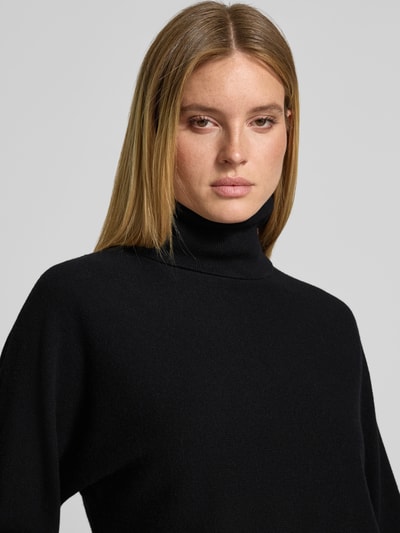 Frauenmodel trägt Regular Fit Pullover aus Woll-Mix mit Kaschmir-Anteil von HERZENS in Schwarz, Rollkragen, elastische Ärmelabschlüsse, Nahaufnahme Oberkörper.