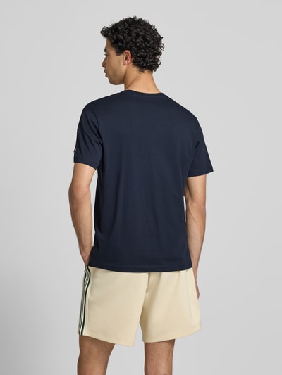 Männermodel trägt T-Shirt mit Label-Stitchings und Rundhalsausschnitt von CHAMPION in Dunkelblau, Reine Baumwolle, Regular-Fit, Rückenlänge bei Größe M 66 cm, Ganzkörperansicht Rückansicht.