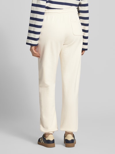 Vrouwenmodel draagt Regular Fit sweatpants met achterzak model 'Nucia' van Mustang in puur katoen, elastische band, steekzakken, binnenbeenlengte 78 cm, bandwijdte 39 cm, kleur crème, rechte pijpen, textuur zacht, geheelbeeld achteraan.