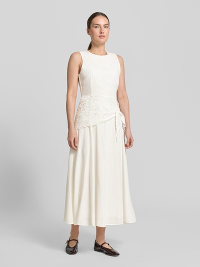 Frauenmodel trägt Midikleid aus Viskose-Mix mit Spitzenbesatz von Mango, elfenbeinfarben, Taillierte Passform, Rundhalsausschnitt, Ärmelloses-Design, Leinen-Anteil, glatte Textur, Ganzkörperansicht von vorne.