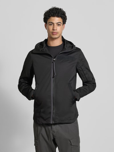 Männermodel trägt Regular Fit Regenjacke mit Reißverschluss Modell 'Batt' von G-Star Raw, schwarze Farbe, Kapuze, Baumwoll-Mix, Ganzkörperansicht von vorne.