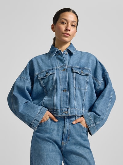 Frauenmodel trägt Relaxed Fit Jeansjacke Modell 'HOLBROOKS' von Drykorn aus reiner Baumwolle, hellblau, Umlegekragen, Brusttaschen, überschnittene Schultern, Ganzkörperansicht von vorne.