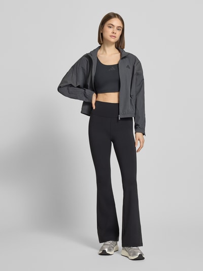 Modelka nosi Crop Top mit Label-Print von adidas Sportswear, czarny, krój przylegający, dekolt U; widok całej sylwetki z przodu.