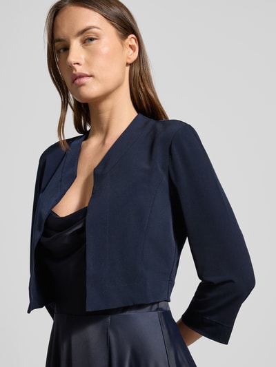 Frauenmodel trägt Bolero mit offener Vorderseite von VM Vera Mont in Dunkelblau, Material-Mix mit Stretch-Anteil, Gerader-Schnitt, Sportmanschetten, Rückenlänge bei Größe 36: 42 cm, Nahaufnahme Oberkörper.