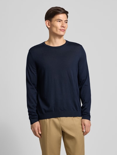 Männermodel trägt Longsleeve aus Schurwolle Modell 'Leno' von BOSS in Dunkelblau, melierte Optik, elastische Abschlüsse, Ganzkörperansicht von vorne.