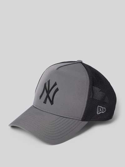 Produktfoto, Trucker Cap mit verstellbarem Riegel auf der Rückseite von New Era, graues Frontpanel, schwarzes Mesh, verstärkter Schirm, Steppnähte, Statement-Applikation z przodu, regulacja z tyłu, tył z siateczki