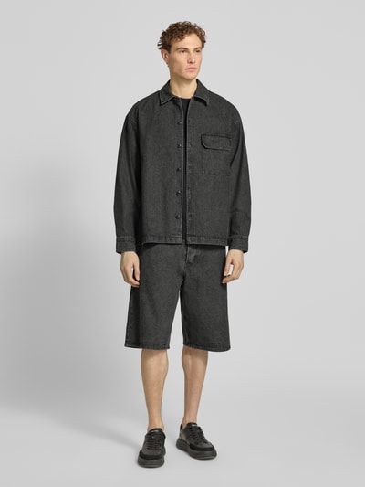 Männermodel trägt Relaxed Fit Hemdjacke mit Brusttasche Modell 'David' von Wood Wood aus dunklem Baumwoll-Mix, Ganzkörperansicht von vorne.