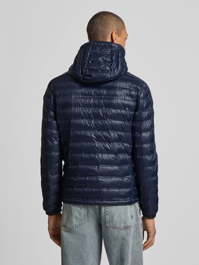 Männermodel trägt dunkelblaue Steppjacke mit Kapuze, Modell 'Charles' von Blauer Usa, Regular-Fit, Rückenansicht, Ganzkörperansicht.