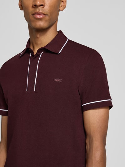 Mannelijk model draagt regular fit poloshirt uit katoenmix van Lacoste in bordeauxrood met witte details, detailopname bovenlichaam, Heren poloshirt