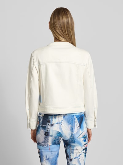 Frauenmodel trägt Jeansjacke mit Motiv- und Statement-Stitching von Marc Cain in Off-White, Baumwoll-Mix mit Stretch-Anteil, Gerader-Schnitt, Rundhalsausschnitt, Knopfleiste, Brusttaschen und seitliche Eingrifftaschen, Rückenlänge bei Größe 36: 50 cm, Schulterbreite: 42 cm, Brustweite: 46 cm, Ärmellänge: 49 cm, Ganzkörperansicht Rückansicht.