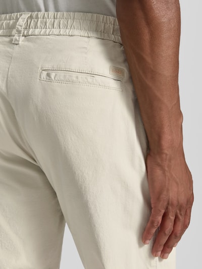Männermodel trägt chinosy Tapered Chino aus Baumwoll-Mix Modell 'CHINO-TAPERED-DS-10' von BOSS Orange, efekt: jednolity kolor, krój tapered fit, szlufki na pasek, zapięcie na guzik i zamek błyskawiczny, tunel (do noszenia wewnątrz lub na zewnątrz), ściągacz: elastyczny, wpuszczane kieszenie, kieszeń z tyłu, materiał: mieszanka bawełny, detal: logo BOSS. Detailaufnahme Rückansicht.