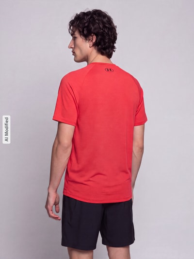 Männermodel trägt Regular Fit Sport-T-Shirt mit Logo-Print von Under Armour in Rot, schwarze Shorts, Ganzkörperansicht Rückansicht, KI-modifiziertes Bild.