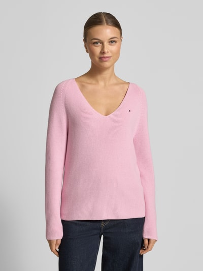 Modelka kobieca nosi Regular Fit Strickpullover aus reiner Baumwolle od Tommy Hilfiger, różowy, rippstrick, długi rękaw, V-dekolt, widok z przodu.