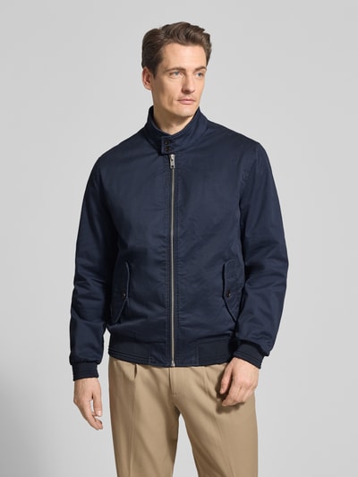 Męski model nosi Jacke mit Stehkragen und Pattentaschen od Christian Berg Men, granatowy, mieszanka bawełny i elastanu, krój regular fit, zamek błyskawiczny, kieszenie z patką, długość tyłu w rozmiarze M 32 cm, szerokość ramion w rozmiarze M 41 cm, szerokość w rozmiarze M 55 cm, długość rękawów w rozmiarze M 67 cm, całkowity widok z przodu.