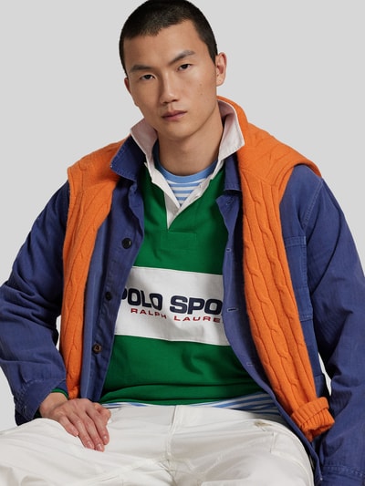 Männermodel trägt Regular Fit Poloshirt aus reiner Baumwolle von Polo Ralph Lauren, Unifarbe grün, Label-Schriftzug, Nahaufnahme Oberkörper.