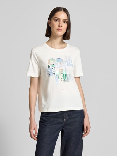 Frauenmodel trägt Damen T-Shirt mit Motiv-Print und Pailletten von Marc Cain, Reine Baumwolle, Regular-Fit, Rundhalsausschnitt, Rückenlänge 55 cm in Größe 36, weiße Grundfarbe, farbige Akzente, glatte Textur, Ganzkörperansicht von vorne.