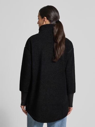 Frauenmodel trägt schwarze Fleecejacke mit Stehkragen Modell 'TOLA' von Didriksons, Relaxed-Fit, strukturierte Oberfläche, Ganzkörperansicht Rückansicht, Reißverschluss, Rückenlänge bei Größe 36: 83 cm, Schulterbreite: 52 cm, Brustweite: 47 cm, Ärmellänge: 56 cm.