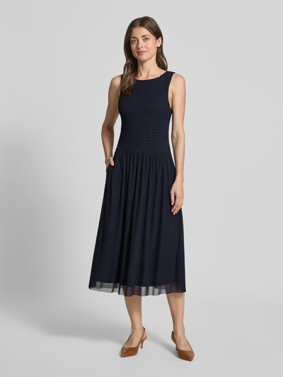 Frauenmodel trägt Midikleid aus Mesh mit Smok-Details von Christian Berg Woman Selection, Dunkelblau, gerader Schnitt, Rundhalsausschnitt, Mesh-Details, Rückenlänge bei Größe 36: 120 cm, Brustweite: 35 cm, Ganzkörperansicht von vorne.