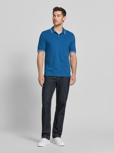 Männermodel trägt Regular Fit Poloshirt mit Logo-Stitching von bugatti in Blau, Reine Baumwolle, Polokragen, kurze Knopfleiste, Label-Detail, Ganzkörperansicht von vorne.