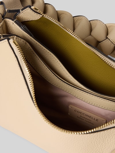 Produktfoto, Handtasche mit Label-Detail Modell 'BOHEME GRANA DOUBLE HOBO' von Coccinelle, beigefarbene grobstrukturierte Oberfläche, Hauptfächer mit Reißverschluss, geflochtener Schultergurt, Innenfutter in Grün und Rosa, Detailaufnahme