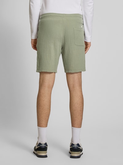 Männermodel trägt groene korte broek van katoenmix met structuurpatroon, steekzakken en trekkoord, model 'AIDEN' van Jack & Jones, Ganzkörperansicht Rückansicht.