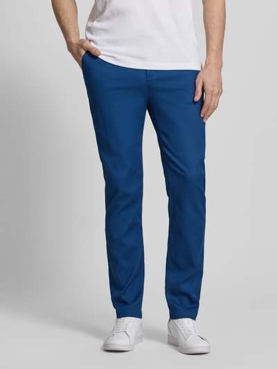 Männermodel trägt Slim Fit Chino aus Baumwoll-Mix von Tommy Hilfiger in Uni-Blau, Piqué-Struktur, seitliche Taschen, Nahaufnahme Unterkörper.