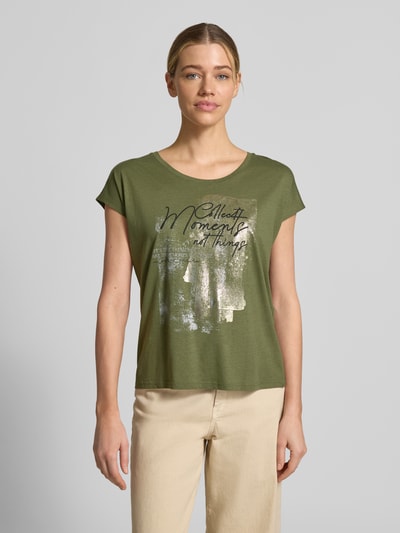 Frauenmodel trägt Damen T-Shirt mit Motiv und Rundhalsausschnitt von Christian Berg Woman, Baumwoll-Viskose-Mix, Regular-Fit, grün, beige Hose, Motiv in Silberoptik, Rückenlänge bei Größe S 55 cm, Ganzkörperansicht von vorne.