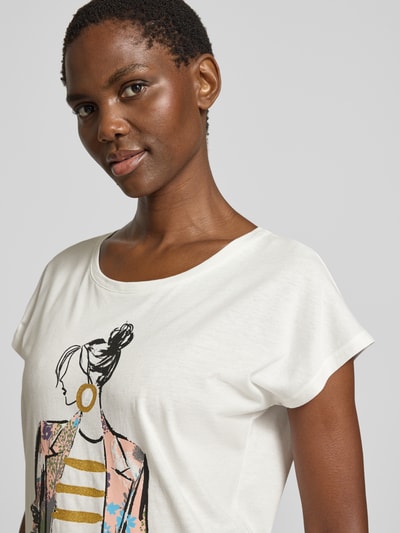 Frauenmodel trägt Damen T-Shirt mit Motiv- und Statement-Print von Christian Berg Woman im Baumwoll-Viskose-Mix, Regular-Fit, Rundhalsausschnitt, in Weiß mit schwarzen, rosa und goldfarbenen Details, Nahaufnahme Oberkörper. Rückenlänge bei Größe S: 57 cm.